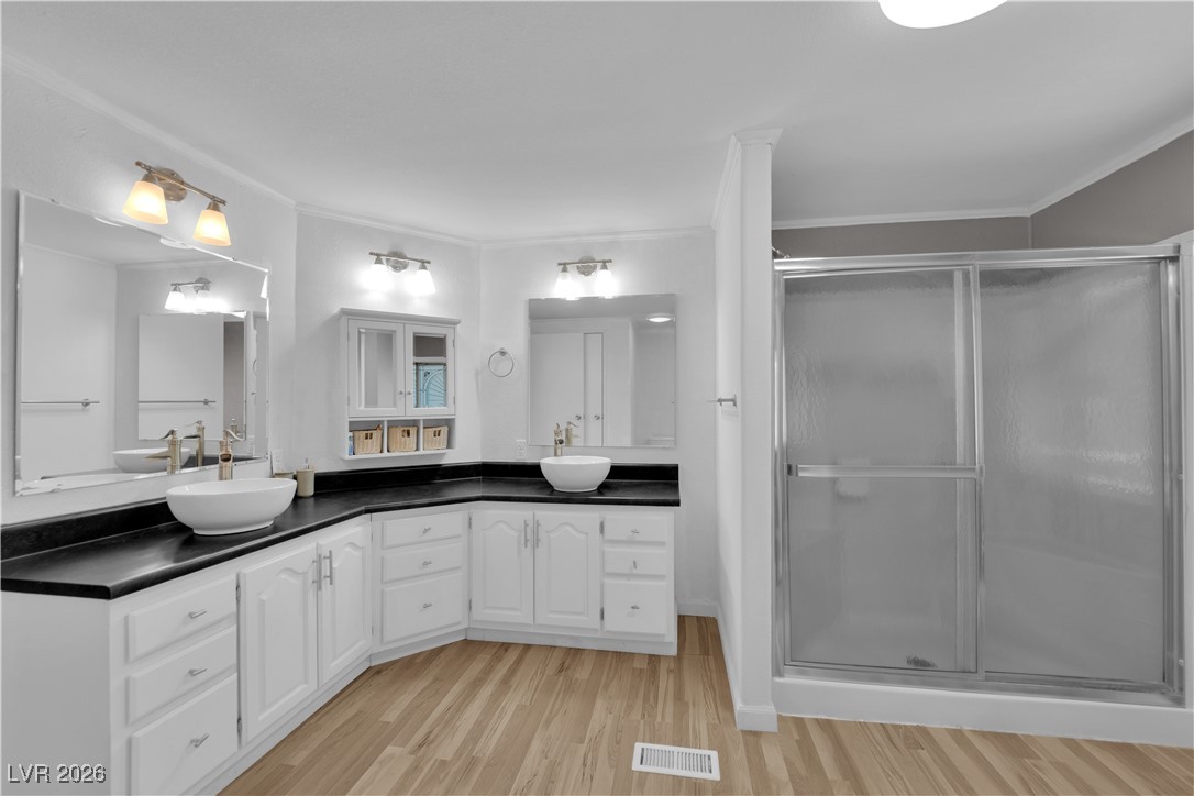 5550 Vicki Ann Road Pahrump, NV 89048 - Photo 17 of 44 Bathroom with double vanity, light wood-type flooring, a shower stall, and crown molding