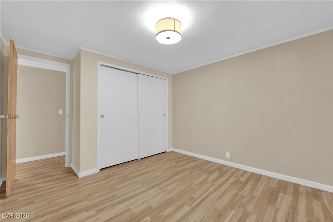 5550 Vicki Ann Road Pahrump, NV 89048 - Photo 22 of 44 Unfurnished bedroom featuring light wood-style floors, a closet, and ornamental molding