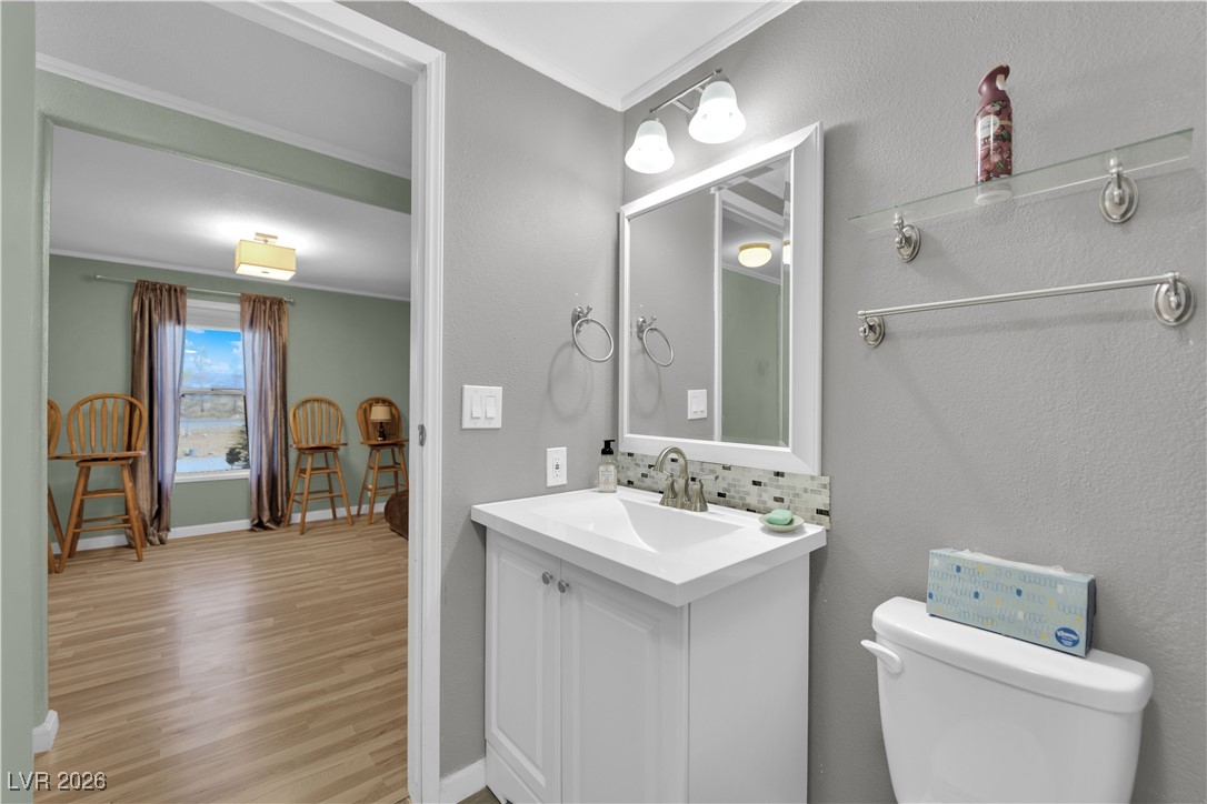 5550 Vicki Ann Road Pahrump, NV 89048 - Photo 27 of 44 Bathroom with vanity, a textured wall, decorative backsplash, light wood-type flooring, and ornamental molding