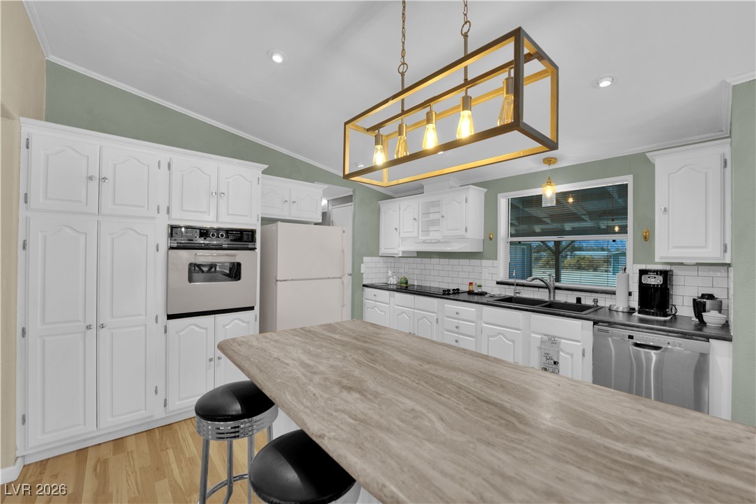 5550 Vicki Ann Road Pahrump, NV 89048 - Photo 32 of 44 Kitchen featuring white cabinetry, pendant lighting, dishwasher, light wood finished floors, and crown molding
