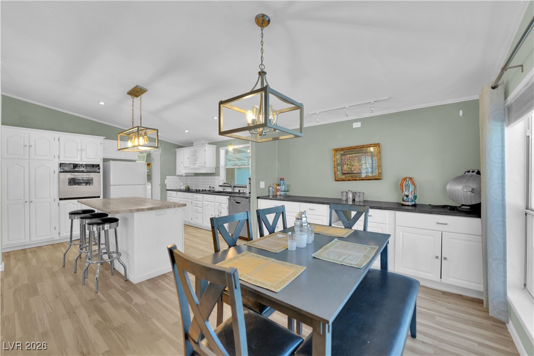 5550 Vicki Ann Road Pahrump, NV 89048 - Photo 36 of 44 Dining area with crown molding, light wood-style flooring, track lighting, and a chandelier