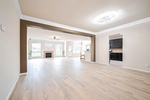 a view of empty room with wooden floor and kitchen
