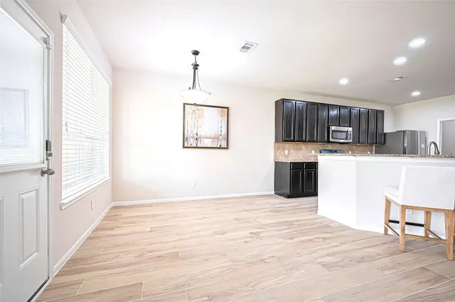 a view of kitchen with stainless steel appliances granite countertop a stove top oven a sink dishwasher and a refrigerator with wooden floor