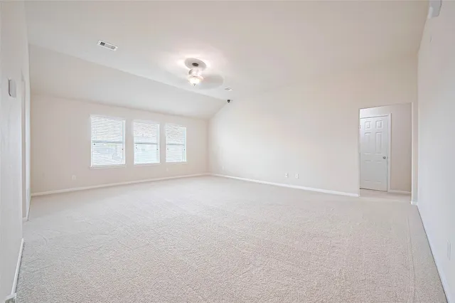 an empty room with windows and chandelier fan