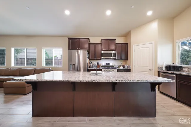 a kitchen with kitchen island stainless steel appliances a sink and a living room