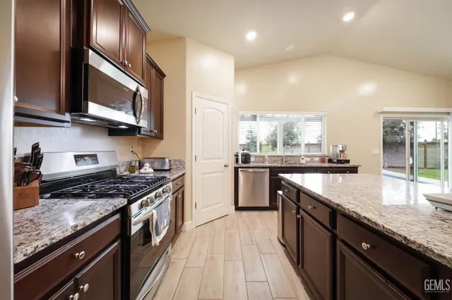 a kitchen with stainless steel appliances granite countertop a stove a sink and a refrigerator