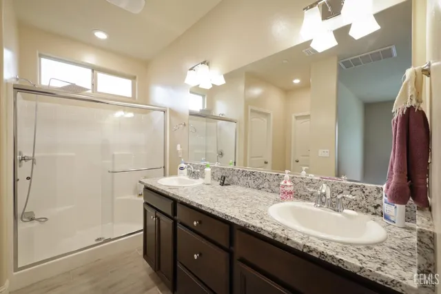 a bathroom with a granite countertop sink a large mirror and a shower