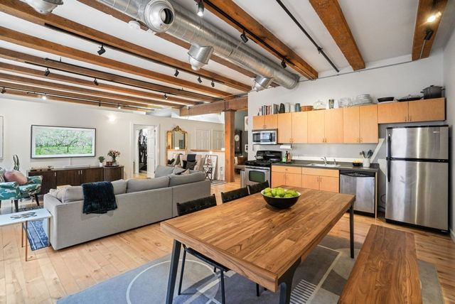 a kitchen with stainless steel appliances granite countertop a refrigerator a sink dishwasher a dining table and chairs with wooden floor