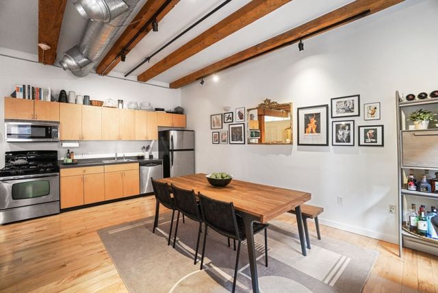 a dining room with stainless steel appliances kitchen island granite countertop furniture and wooden floor