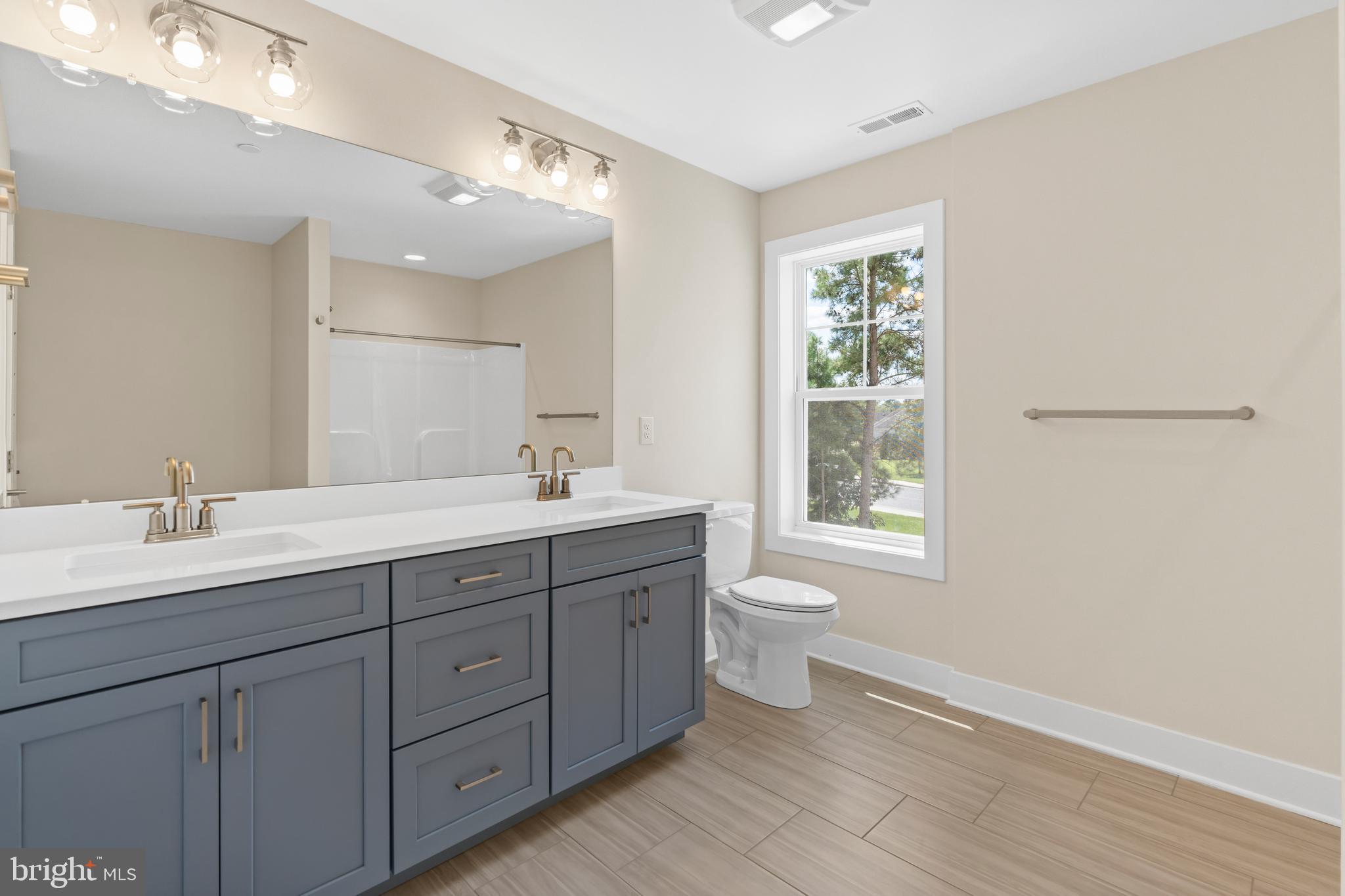 22580 Hummingbird Road, Unit 17 Ellendale, DE 19941 - Photo 36 of 75 a bathroom with a double vanity sink a toilet and a window