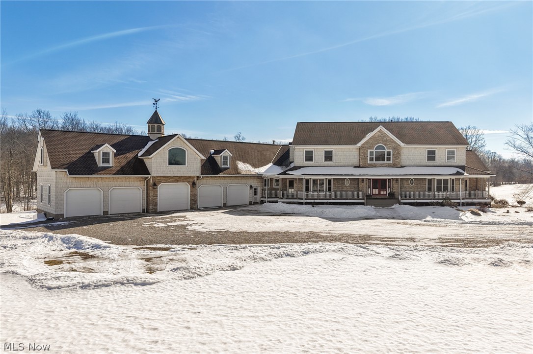 View of front of house featuring covered porch, a 5-car garage, and driveway
