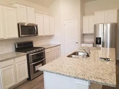 a kitchen with granite countertop a sink stove and refrigerator