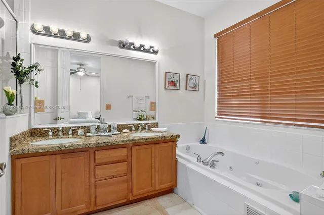 a bathroom with a granite countertop sink mirror and a bathtub
