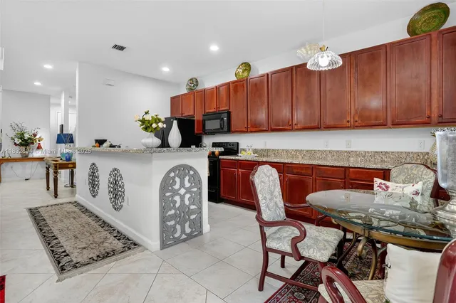 a kitchen with stainless steel appliances granite countertop a table chairs sink and cabinets