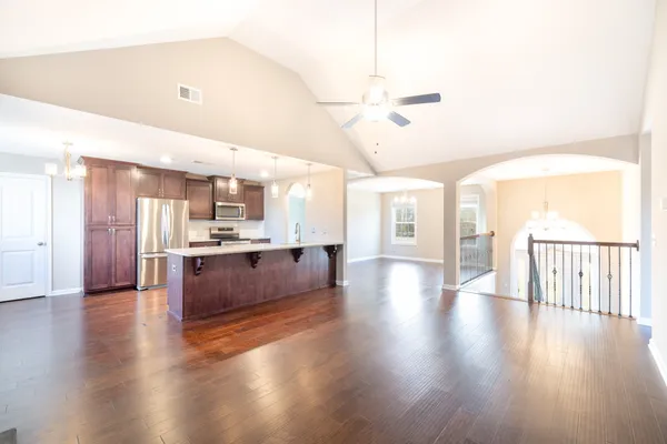 a large kitchen with stainless steel appliances kitchen island wooden floors and living room view