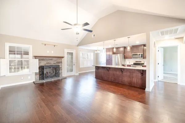 a big room with wooden floor a kitchen view and a chandelier