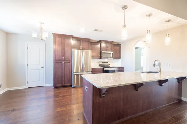 a kitchen with stainless steel appliances granite countertop a sink a refrigerator and a stove