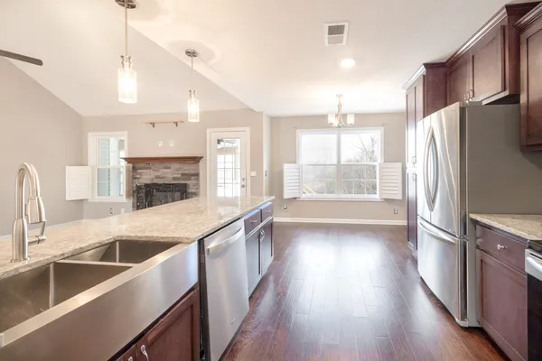 a kitchen with stainless steel appliances granite countertop a refrigerator a sink dishwasher a oven with wooden floors