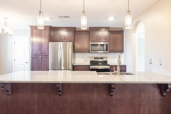 a kitchen with stainless steel appliances a sink a refrigerator a stove and a center island