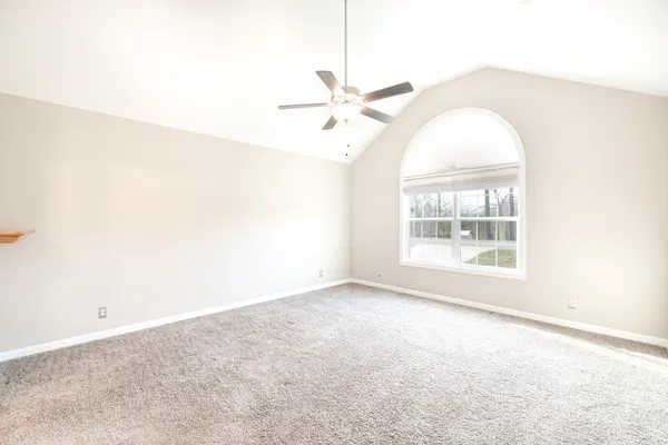 an empty room with windows and ceiling fan