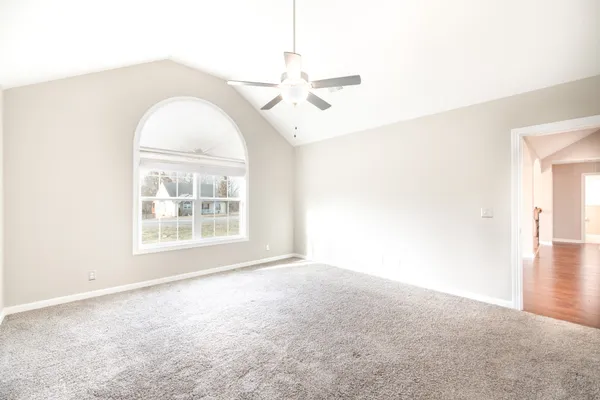 an empty room with windows and fan