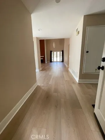 a view of an empty room with a window and wooden floor