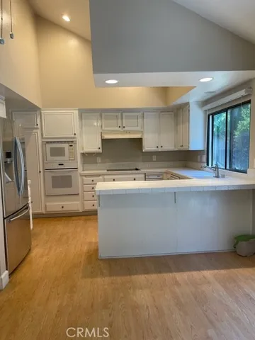 an empty room with wooden floor and windows with curtains