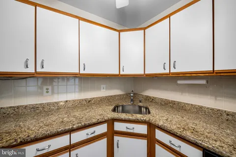 a kitchen with granite countertop white cabinets and a sink