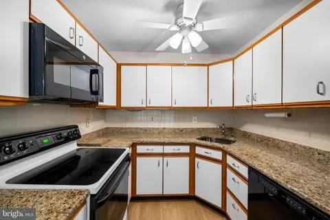 a kitchen with granite countertop a sink a stove and cabinets