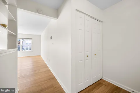 a view of a hallway with wooden floor and a bathroom
