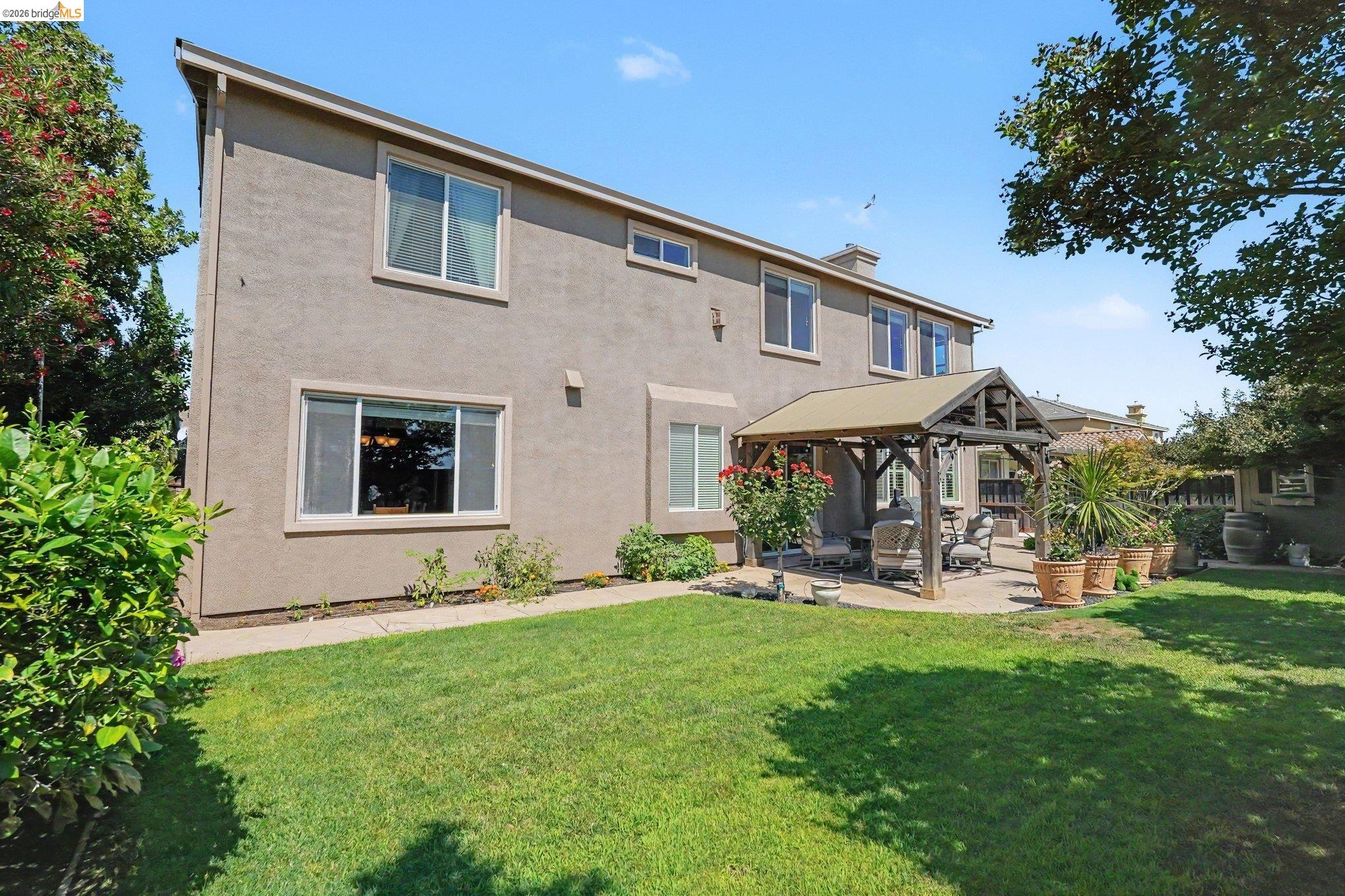 106 Little Ranch Circle Oakley, CA 94561 - Photo 28 of 34 Rear exterior featuring a covered patio, stucco siding, multiple windows, and a green lawn