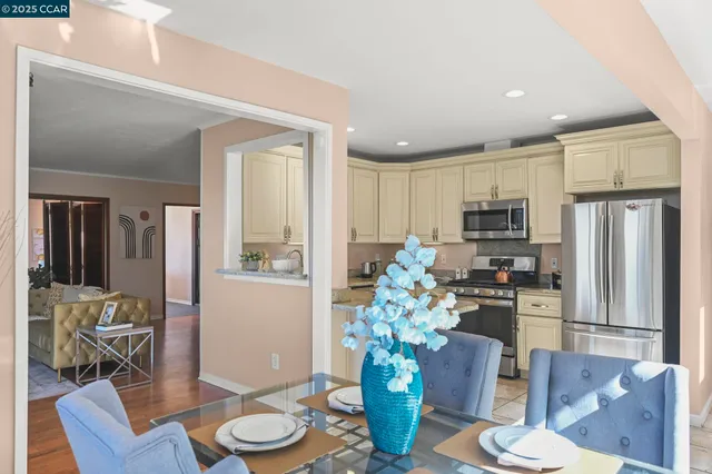 a living room with furniture potted plant and kitchen view