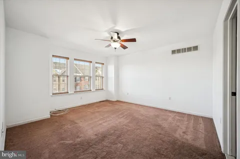 an empty room with chandelier fan and windows