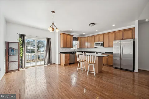 a kitchen with stainless steel appliances granite countertop a refrigerator a stove top oven a sink dishwasher and white cabinets with wooden floor next to windows