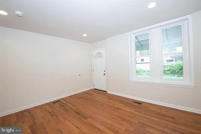 an empty room with wooden floor and windows