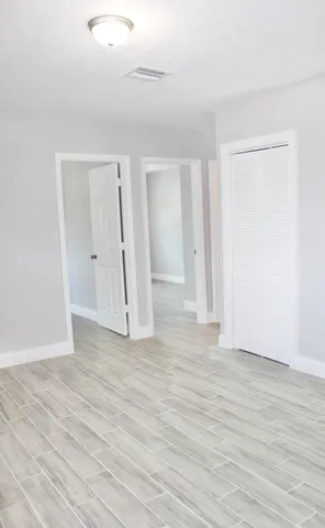 a view of an empty room with wooden floor and closet