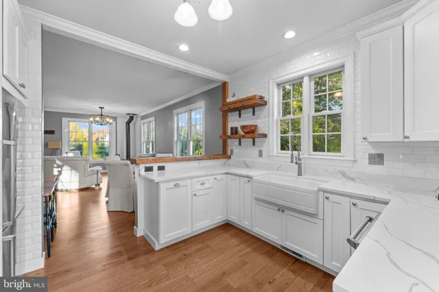 a large white kitchen with lots of counter space a sink and a large window