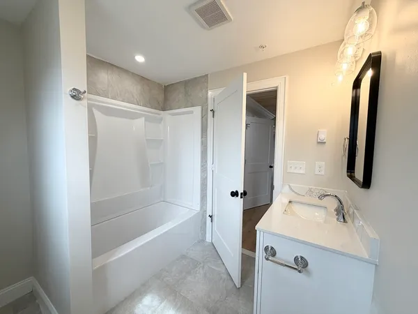 a bathroom with a tub sink and mirror