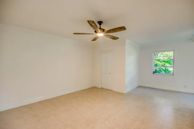 an empty room with a window and a fan