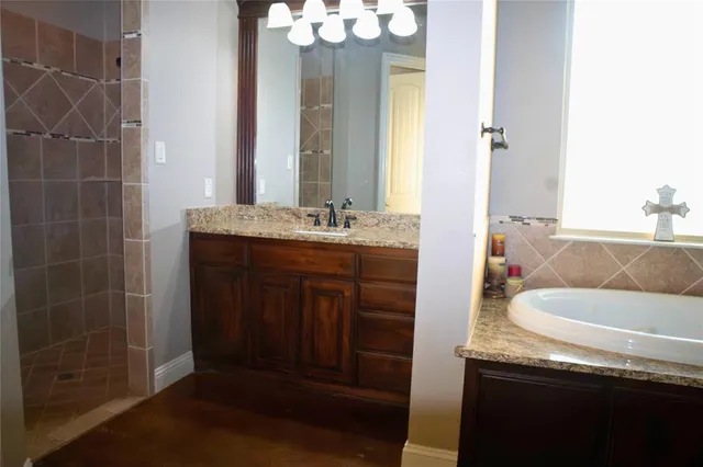 a en suite bathroom with a granite countertop sink and a mirror