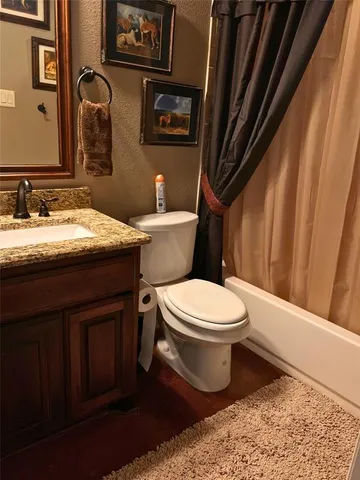 a bathroom with a granite countertop toilet sink and mirror