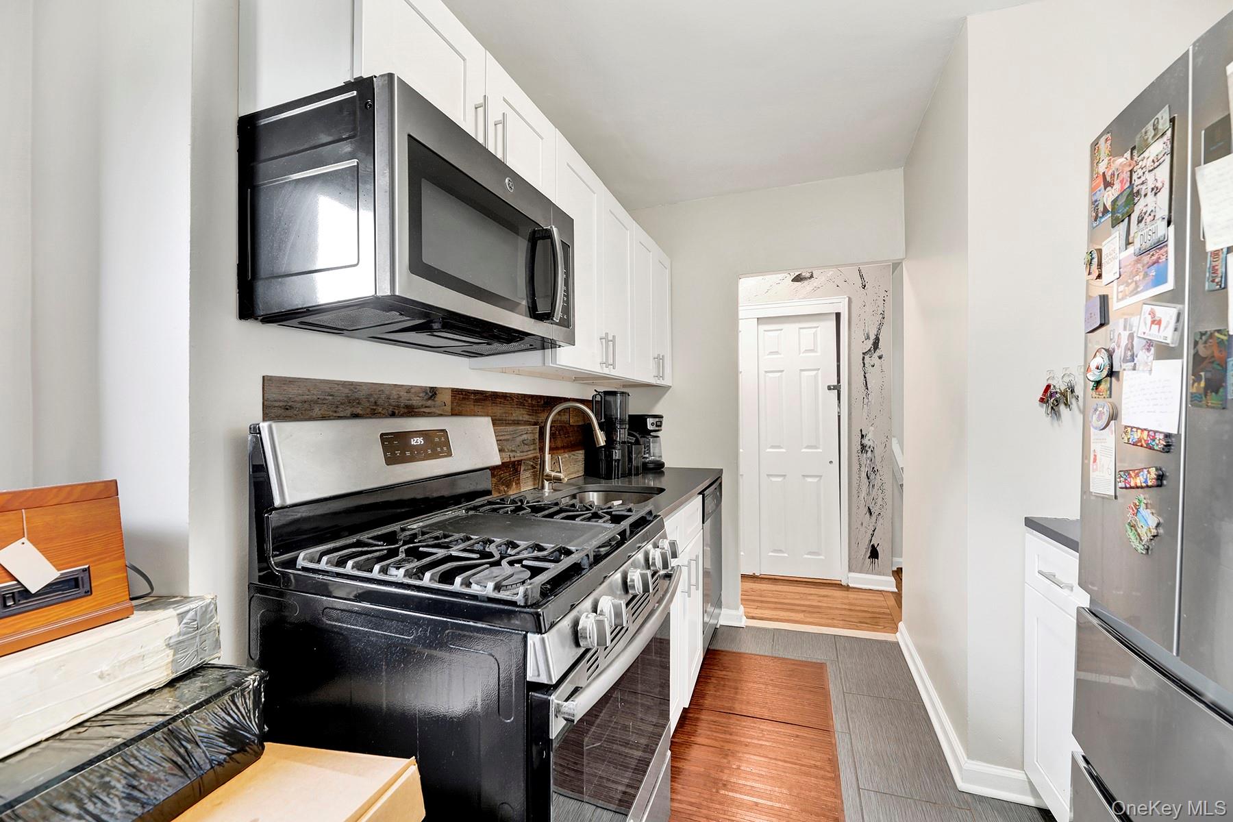 285 East 35th Street, Unit 6E Brooklyn, NY 11203 - Photo 4 of 21 Kitchen featuring stainless steel appliances, white cabinetry, and dark countertops
