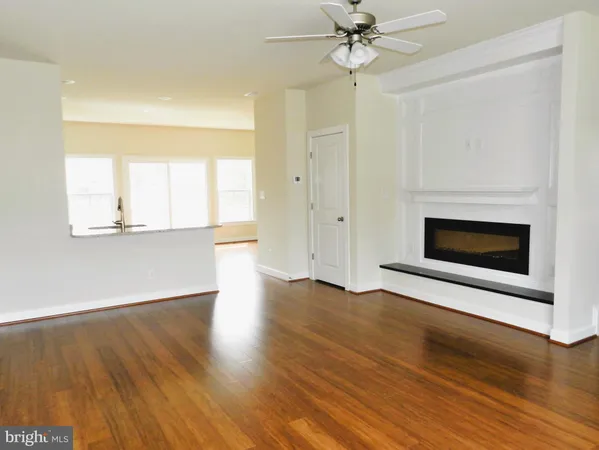 an empty room with wooden floor a ceiling fan and windows