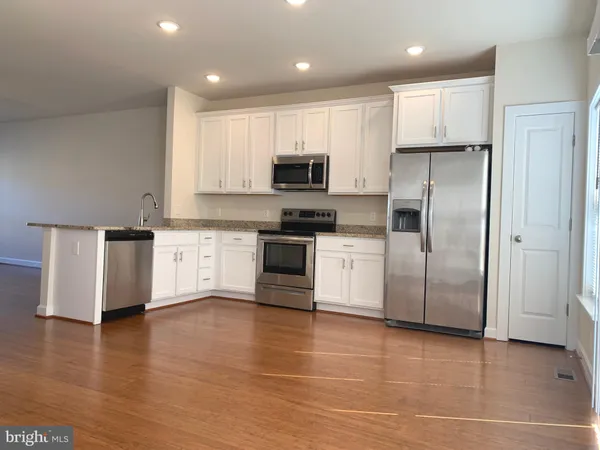 a kitchen with granite countertop a refrigerator and a stove top oven