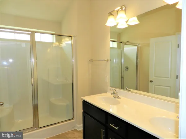 a bathroom with a granite countertop sink a mirror and a shower
