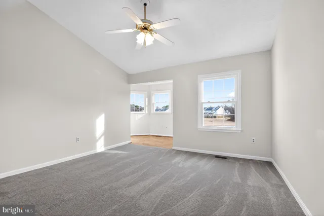 an empty room with windows and ceiling fan