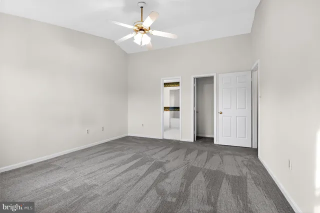 an empty room with a windows and a ceiling fan