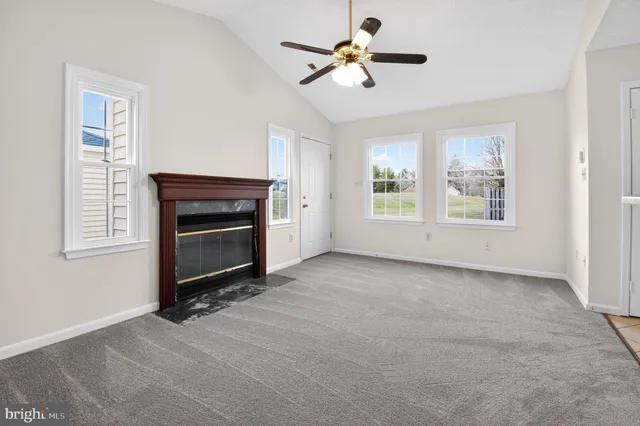a view of a livingroom with a fireplace a ceiling fan and windows