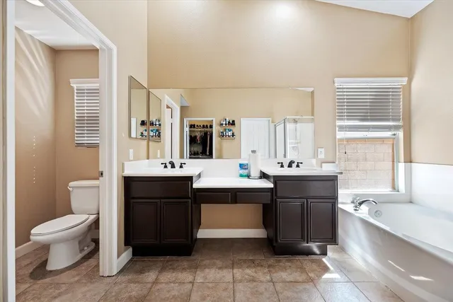 a spacious bathroom with a bathtub sink vanity mirror and toilet
