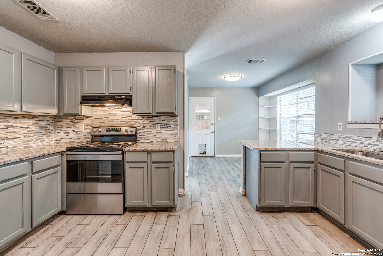 8009 Forest Ash Live Oak, TX 78233 - Photo 12 of 33 a kitchen with stainless steel appliances wooden floor sink and wooden cabinets